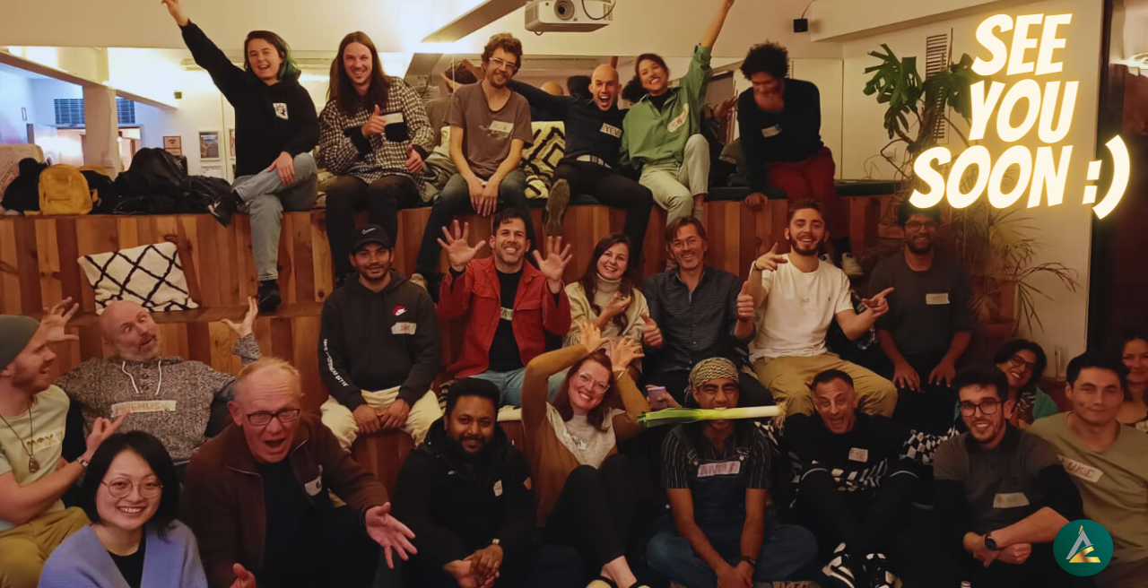 A packed Evolution Tribe room in Lisbon โ dozens of smiling people waving at the camera